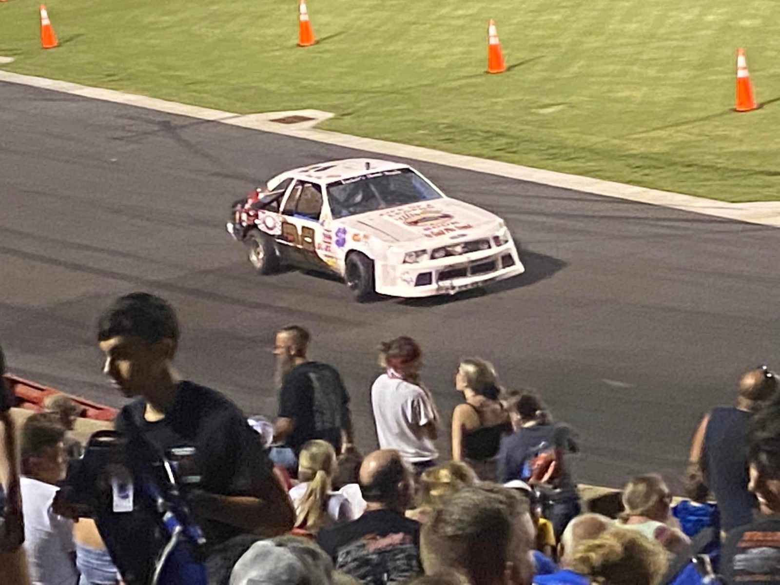 The #28 coming off the turn at night with fans in the stands